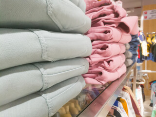 A closeup side angle view of a stack of pants placed on the shelf.