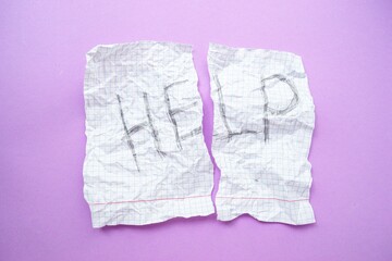 Text help on a white sheet of paper in a cage on a purple background. The concept of helping those in need.