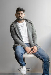 Casually handsome. Studio shot of handsome young man sitting on the chair and looking at camera with attitude