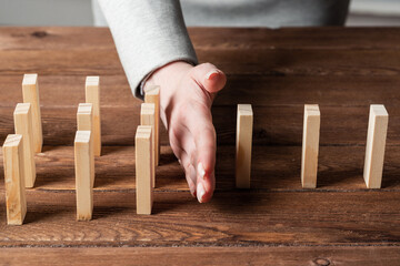 Businesswoman protecting dominoes from falling