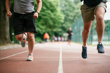 Fototapeta premium Young men training on a race track. Two young friends running on the athletics track 