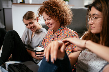 Happy businesswomen talking and laughing in office. Beautiful women on coffee break.	