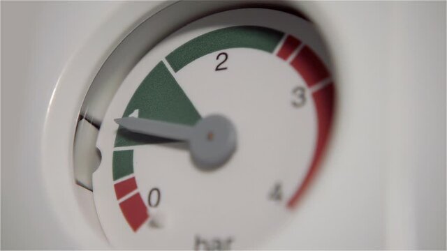 On the white side of the equipment, the pressure gauge needle deflects when the pressure in the piping system changes, but is in the safe green zone. Close up