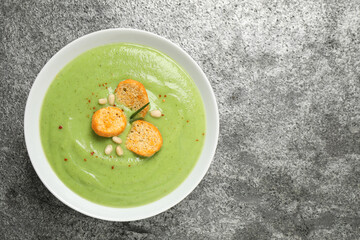 Tasty homemade zucchini cream soup on grey table, top view. Space for text