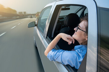 Woman passenger sitting in the backseat and looking out the window when her self-driving car rides...