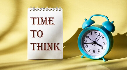 The inscription Time to think on a notepad on a light background, next to an alarm clock