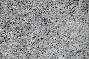 gray porous concrete wall with small holes and deep relief. rough surface texture