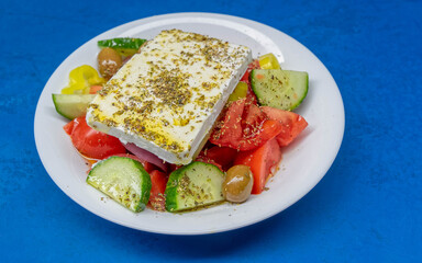 fresh Greek salad plate on vibrant blue table background