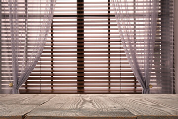 Wooden table and window with blinds on background