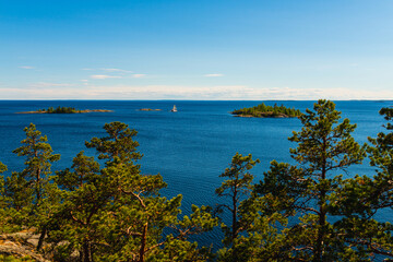 Sunny day on the lake. Bright colorful photo of blue sky, trees and lake in Karelia, Russia.