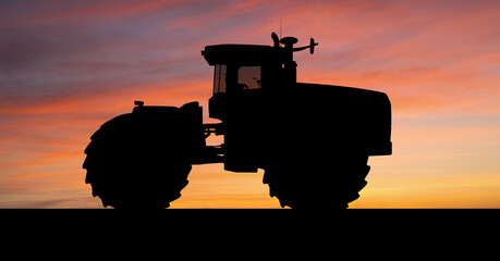 Silhouette of an agricultural tractor against the sunset sky