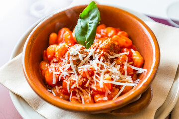 Terrina di terracotta con gnocchi al sugo di pomodoro, formaggio e basilico