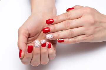 Red manicure with crystals and white spider web on short square nails close-up on a white background. 