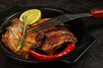 Baked pork ribs with lemon and hot pepper and a barbecue fork