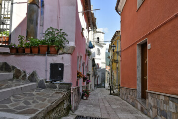 A narrow street between old houses with doors and windows decorated with plants and flowers in San Gregorio Matese, a mountain village in the province of Caserta.