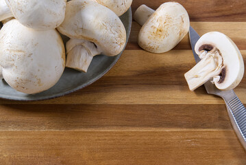 Fresh champignon mushrooms on wooden cut board. Close-up white sliced champignon.