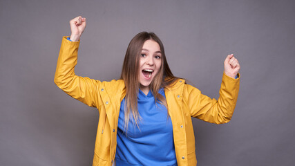 Happy young girl with raised fists, cheers, victory.