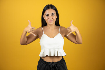 Young beautiful woman over isolated blue background shouting with crazy expression doing rock...