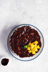 Delicious no baked cheesecake with fresh apricots, chocolate glaze and mint. Light grey stone background. Top view.