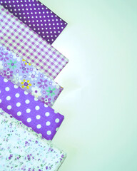 A set of white-dotted and floral cotton fabrics in lilac and mauve with white space for text. Vertical view. Scrapbooking and DIY. Hobby and needle work background. 