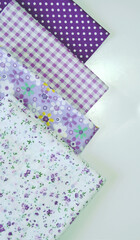 A set of white-dotted and floral cotton fabrics in lilac and mauve with white space for text. Vertical view. Scrapbooking and DIY. Hobby and needle work background. 