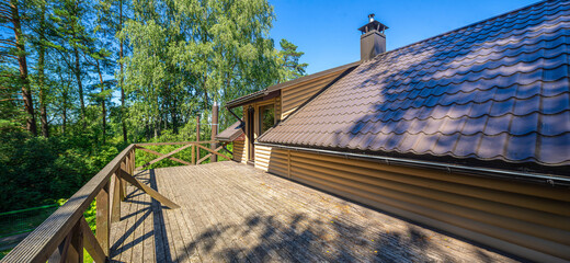 Large wooden terrace on the second floor in private country house near the forest. Sunny summer day.