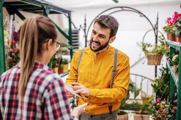 Young smiling male employee talking with her boss and showing him offers that customers want....
