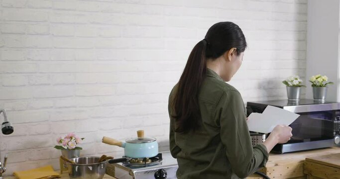 Young happy asian korean woman surprised to receive good news reading letter in kitchen while walking around at home. cheerful student girl got admission of college laughing joyful by window.