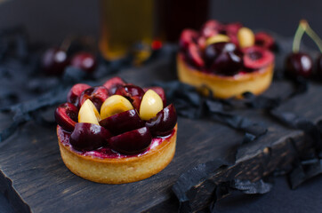 Mini tarts decorated with fresh cherry on black background