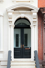 Vintage shabby-looking entry door in New York decorated with arch and corbels. USA. © alexzosimov