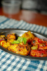 Indian veg meal dish of roasted potatoes and tomato