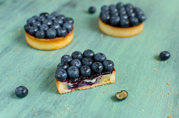 Mini tarts decorated with fresh blueberry on green background
