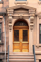 Double wooden vintage arched entry door decorated with arch, corbels and pilasters. New York. USA.