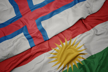 waving colorful flag of kurdistan and national flag of faroe islands.