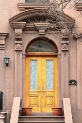 Fototapeta na wymiar Double wooden vintage arched entry door decorated with arch, corbels and pilasters. New York. USA.