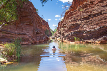 A man is swimming in Mamersley Gorge in Karijini National Park, Western Australia 