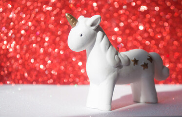 Little unicorn on a shiny bright red background with. The concept of magic, childhood dreams, a modern trend for universal advertising
