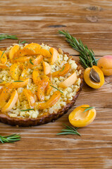 Pie with fresh apricots and rosemary on a light wooden background