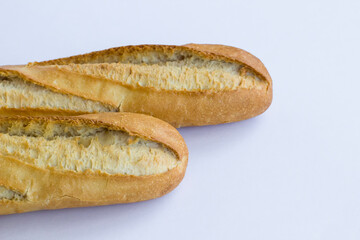 Fresh baguette breads on white surface with knife,above view.
