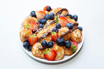 Little pancakes. Dutch poffertjes with blueberries  and strawberries .
