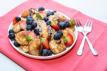 Little pancakes. Dutch poffertjes with blueberries  and strawberries .