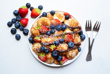 Little pancakes. Dutch poffertjes with blueberries  and strawberries .