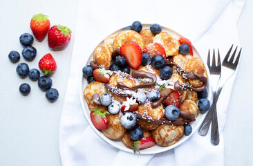 Little pancakes. Dutch poffertjes with blueberries  and strawberries .