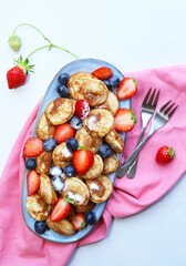 Little pancakes. Dutch poffertjes with blueberries  and strawberries .