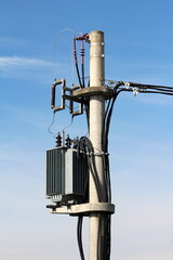 Strong metal electric power transformer with grey utility box mounted on high concrete utility pole...