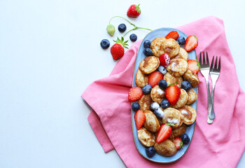 Little pancakes. Dutch poffertjes with blueberries  and strawberries .