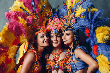 Three Women smiling portrait in brazilian samba carnival costume with colorful feathers plumage. - obrazy, fototapety, plakaty