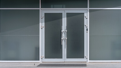 empty gray wall exterior with closed door in white steel frame at city street front view