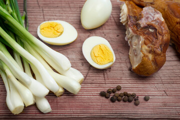 Boiled eggs, fresh chives and smoked chicken laid out on a board