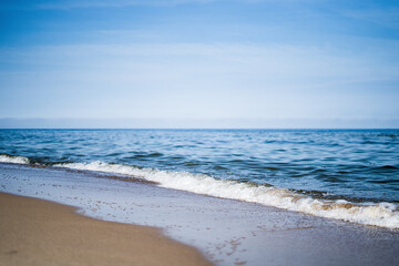 Fototapeta na wymiar blue waves crashing on the sand shore of the Baltic Sea